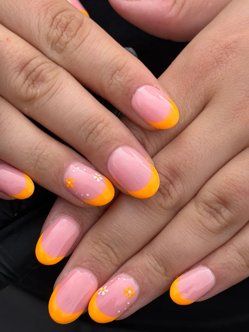 Pink nails with neon orange French tips and tiny painted flowers, by Rosie Mae Beauty